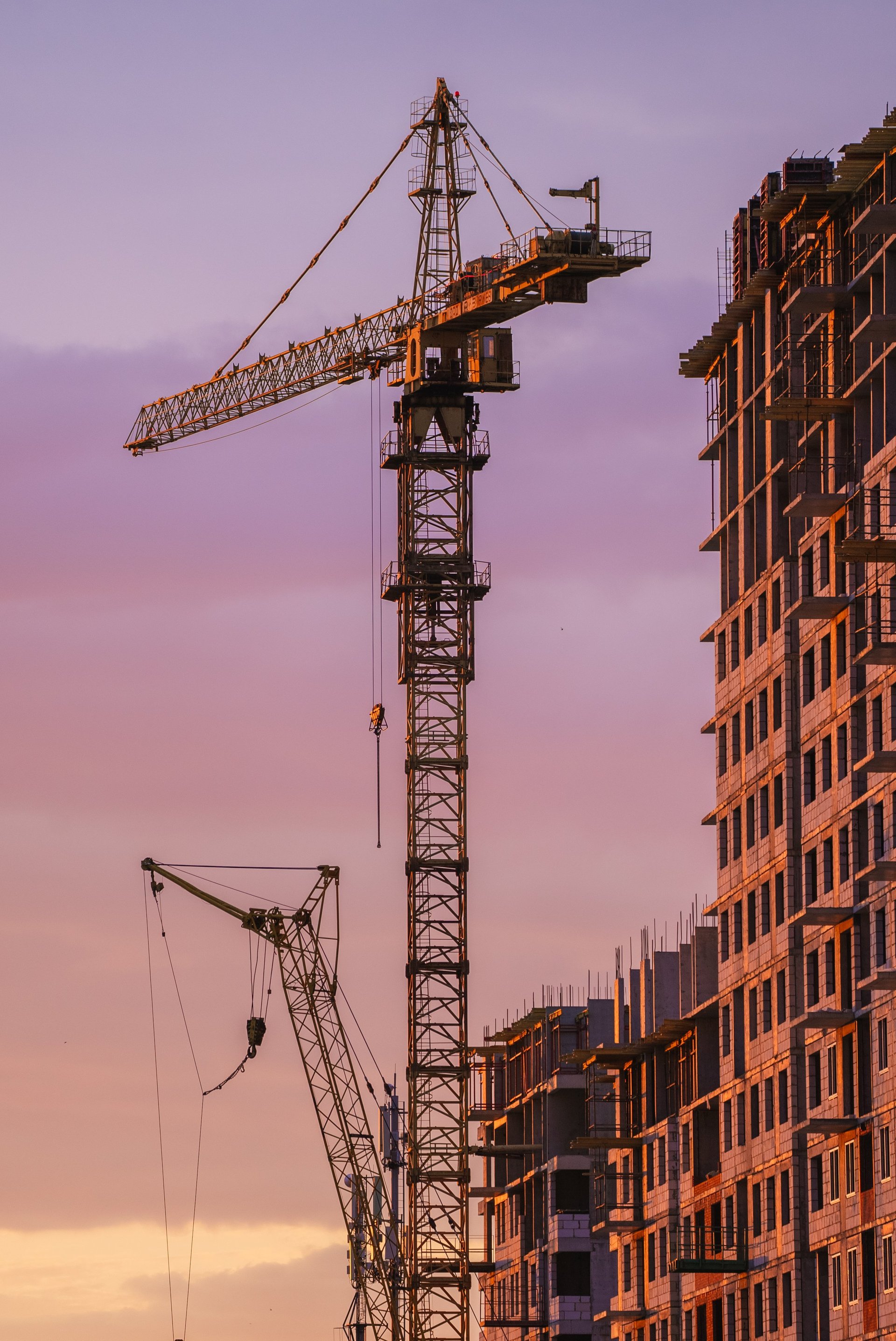 Tower cranes working on residential apartment building at sunset